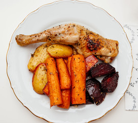 Colorful delicious food in white plate - view from above - homemade food carrots, chicken, potatoes, and sugar beet ass seasoned with dried herbs