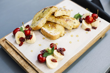 Fried bread with sugar with decoration of chopped banana and cherries
