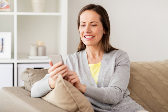 happy woman texting message on smartphone at home - Powered by Adobe