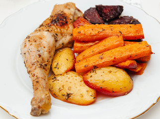 Delicious food in white plate - view from above - homemade food carrots, chicken, potatoes, and sugar beet ass seasoned with dried herbs