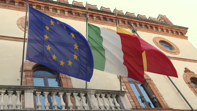 Italian and European flags on the historic building of Town Hall of Ravenna. Slow motion.