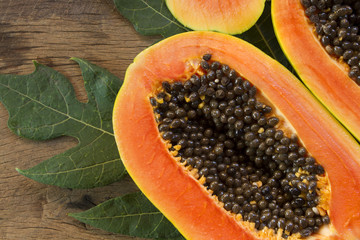 close up of papaya slice with leaf on wooden