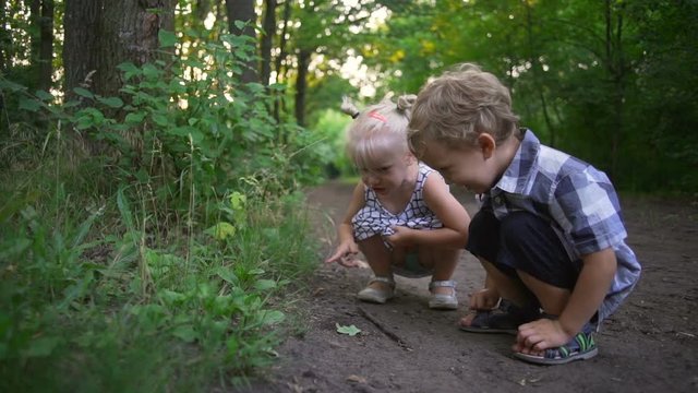 Small boy and girl sitting squat road park smiling jump sunny rapid slow motion