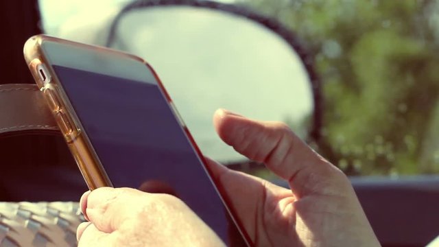 Woman on smartphone in car on summer day while driving on highway