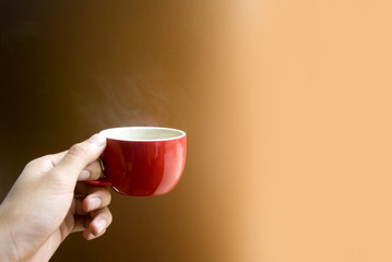 hand pick red cup coffee on orange background