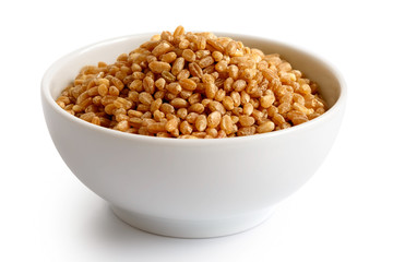 Spelt groats in white ceramic bowl isolated on white. 