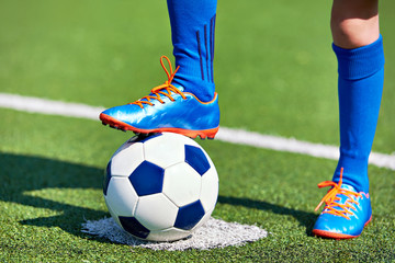 Obraz premium Boy soccer in football boots with ball on grass