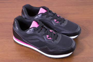 Black sneakers. Closeup of a pair of black unbranded sneakers on wooden background.