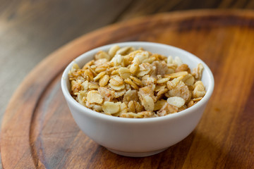 Granola or muesli in white ceramic bowl over wooden table.