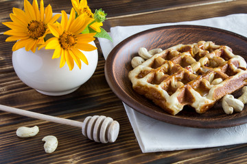 Wafflers with nuts and honey in the brown plate on the wooden background