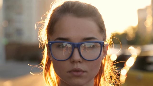 Girl in glasses on the background of sunset