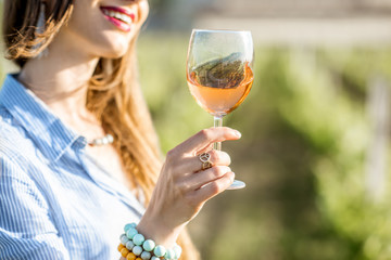 Young woman tasting wine standing outdoors on the vineyard in Bordeaux region during the sunset in France © rh2010