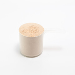 heap of isolate and chocolate protein powder with plastic spoon on white background
