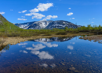 Naklejka na ściany i meble View of the Hibiny (Khibiny) Mountains with a reflection in the water of a small river. Kirovsk, Kola Peninsula, Murmansk region, Russia.