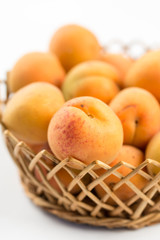 Fresh apricot in the wicker bowl above white background.