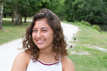 Portrait of curly cute teenage girl in a white dress over outdoor natural field