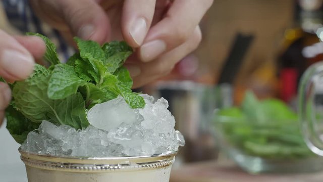 A bartender places a mint garnish in a Mint Julep cocktail. Shot with a RED Dragon digital cinema camera.