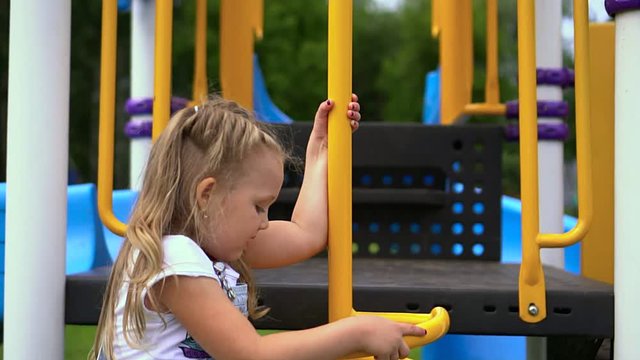The little girl the blonde gets on a slide on the platform in the park