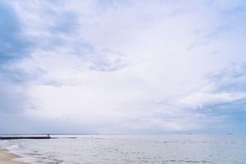 Silhouette of a young couple of unrecognizable girl and her boyfriend standing on a concrete pier on the background of evening sky and sea.