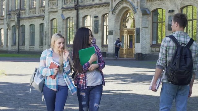 Female students walking near university and smiling to men. Flirt. Slow-motion