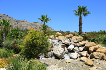 Piękne palmy przy kamienistym wodospadzie na wyspie Rodos w Grecji.