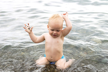 Cute baby boy splashing in the sea waves