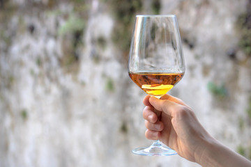 female hand holding a wine glass, rusty background with copy space (neutral style picture)