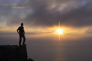 Man doing sport on top of mountain at sunset