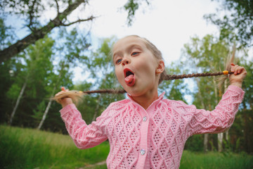 Little funny girl holding her two plaits