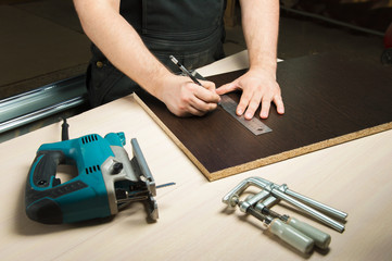 Male hands draw a pencil on the ruler