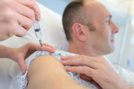 Man looking away while having injection in the arm