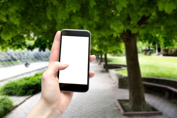 Smartphone with blank screen and copy space holding a woman in the hand on a walk in the park.