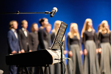 Obraz premium Mikrofon i muzyka stoją przed fortepianami elektrycznymi na scenie teatru