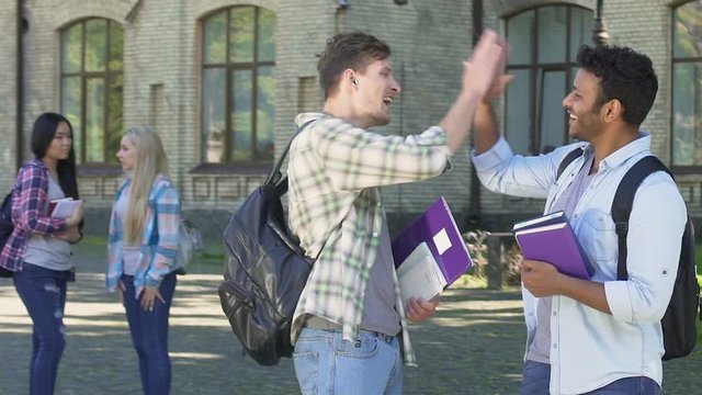 Two multiracial men talking and giving high five each other. Students life