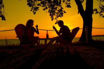 Fototapeta na wymiar couple drinking wine against sunset as silhouette
