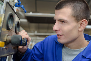 Young worker turning dial on machinery