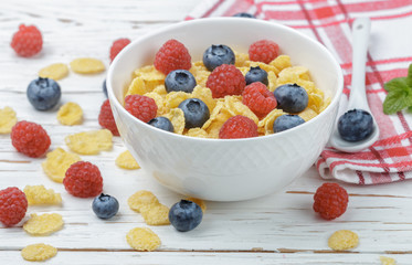 Cornflakes with fresh berries raspberry and blueberry in white bowl on the table. Healthy Breakfast. Selective focus. Top view