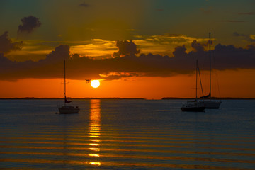 sunset over ocean with anchored boats in bay 