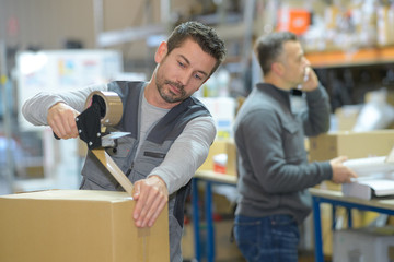 man working at warehouse while manager on the phone - obrazy, fototapety, plakaty