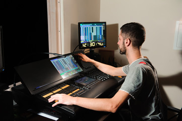A lighting engineer works with lights technicians control on the concert show. Professional light...