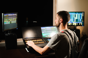 A lighting engineer works with lights technicians control on the concert show. Professional light...