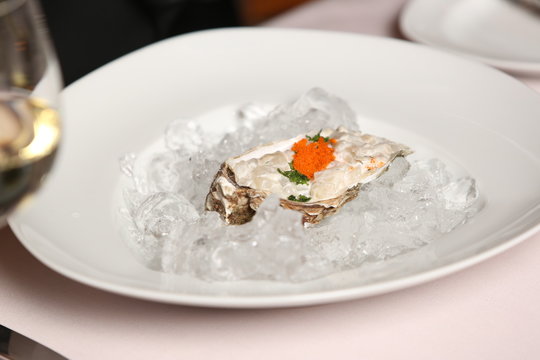 Oyster with red caviar on ice cubes. Close up