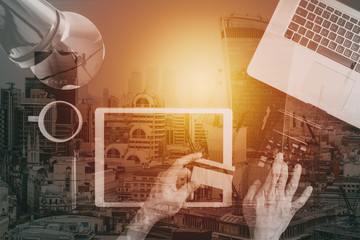 Internet shopping concept.Top view of hands working with laptop and credit card and tablet computer on dark wooden table background with buildings exposure