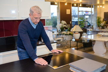 Man looking at induction hob in store - obrazy, fototapety, plakaty