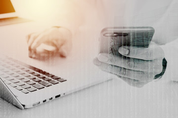 close up of businessman using mobile phone and laptop computer on white desk in modern office