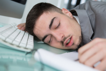 Young man asleep next to his computer