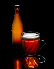 Vintage big beer glass and bottle on a black background