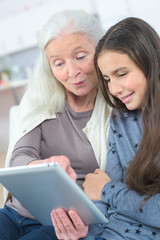 Elderly and young females looking at tablet computer