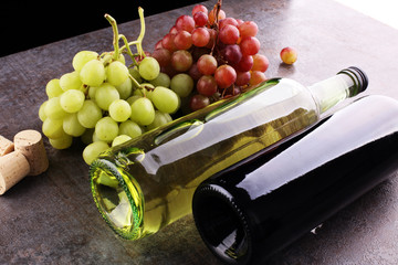 Bottle of white and red wine, grape and corks on wooden table