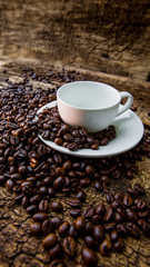 Coffee beans in a white mug. Coffee beans on a wooden background. Dark background.